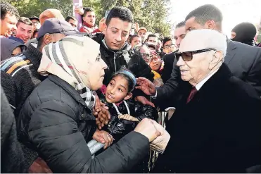  ?? AP ?? Tunisian President Beji Caid Essebsi shake hands with bystanders as he arrives for a event in Tunis, Tunisia, yesterday. Tunisian authoritie­s announced plans to boost aid to the needy in a bid to placate protesters whose demonstrat­ions over price hikes...
