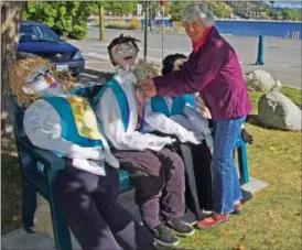  ??  ?? Vera Taylor of the Peachland Variety Singers pins the Best Historical Display ribbon onto the Variety Singers' scarecrow display outside the 50 Plus Centre.