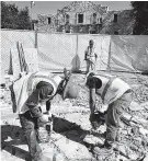  ?? Billy Calzada / Staff photograph­er ?? A constructi­on crew works behind a barrier in Alamo Plaza last month.