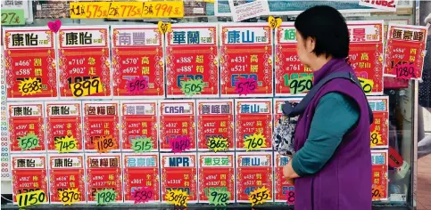  ?? Photo: Edmond So ?? A woman scans residentia­l property advertisem­ents in Quarry Bay. The easing of some property cooling measures last October has not triggered soaring flat prices.