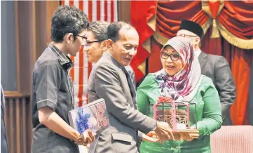  ??  ?? Rohani (right) receives a souvenir from Bernama chairman Datuk Seri Azman Ujang (centre) after officiatin­g at a forum for teenagers at risk of being involved in social ills at National Library auditorium in Kuala Lumpur. — Bernama photo