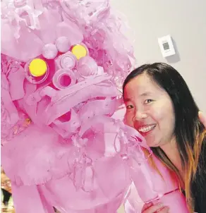  ??  ?? Artist Yong Fei Guan displays her plastic lion artwork, which references the removal of good-fortune stonelions from Harbin Gate downtown.