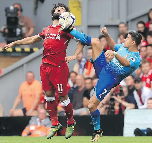  ?? — THE ASSOCIATED PRESS ?? Liverpool’s Mohamed Salah, left, and Arsenal’s Alexis Sanchez battle for the ball during English Premier League action Sunday in Liverpool. Liverpool was a 4-0 winner with Salah scoring once and setting up another goal off the head of Daniel Sturridge.