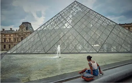  ?? (Getty) ?? Al Louvre A Parigi, investita da un’ondata di calore, una donna trova ristoro bagnandosi i piedi nell’acqua della famosa Piramide del Louvre