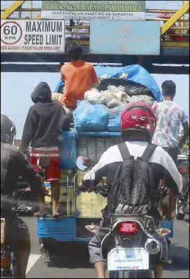  ?? BOY SANTOS ?? Workers hold on to a jeepney overloaded with fruits and vegetables along Commonweal­th Avenue in Quezon City yesterday.