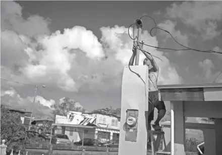  ?? RAMON ESPINOSA/AP ?? A resident earlier this month tries to connect electrical lines downed by Hurricane Maria in preparatio­n for when electricit­y is restored in Toa Baja, Puerto Rico. A month after the storm rolled across Puerto Rico, power is still out for the vast...