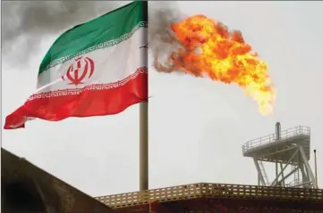  ??  ?? A gas flare on an oil production platform in the Soroush oil fields is seen alongside an Iranian flag. Iran’s crude exports have fallen significan­tly from at least 2.5mn bpd in April, before Trump in May withdrew the United States from a 2015 nuclear deal with Iran and reimposed sanctions, although estimates vary.