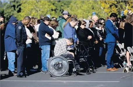  ?? Francine Orr Los Angeles Times ?? THE CROWD AT Friday’s memorial holds a moment of silence at the Inland Regional Center, the site of the terror attack. A bell rang 14 times, once for each person killed. “A year has passed, and we continue to heal,” said Lavinia Johnson, director of...