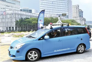  ??  ?? Dr Mahathir seen together with Gobind on the back of the ‘Autonomous Electric Vehicle’ during the launch of Malaysia 5G Showcase in Putrajaya. — Bernama photo