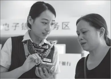  ?? XU JINBAI / FOR CHINA DAILY ?? An employee of China Constructi­on Bank helps a client at a branch in Haian, Jiangsu province. CCB has set up 29 overseas branches in 27 countries and regions.