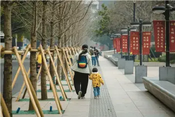  ?? QILAI SHEN/THE NEW YORK TIMES 2023 ?? A woman and child walk along a Shanghai street. China’s birthrate has declined for years.