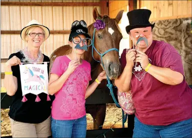  ??  ?? Above: Shelley Wolf, Angela Tanner and Shana Cook posed with Rain, a therapeuti­c riding horse, at the hug-a-horse photo booth. Left: guests enjoyed hamburgers and live music on the lawn during Courage Fest.