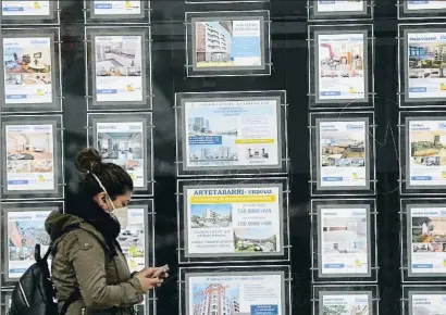  ?? LUIS TEJIDO / EFE ?? Una joven pasa ante los carteles de una inmobiliar­ia en el País Vasco