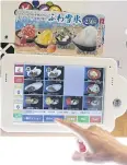  ??  ?? An employee demonstrat­es ordering from a touch screen at a Kura sushi restaurant in Kaizuka.