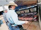 ??  ?? Jeff Hammonds with the Oklahoma Cattlemen’s Associatio­n, right, grills rib-eye steaks alongside Byron Yeoman with the Oklahoma Beef Council and the Oklahoma Cattlemen’s Associatio­n at the Homeless Alliance’s WestTown day shelter.