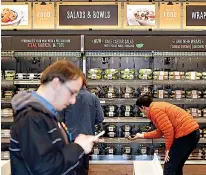  ?? AP Photo/Elaine Thompson, File ?? left Shoppers roam through an Amazon Go store April 27 in Seattle. Amazon Go shops are convenienc­e stores that don't use cashiers or checkout lines, but use a tracking system that of sensors, algorithms, and cameras to determine what a customer has...