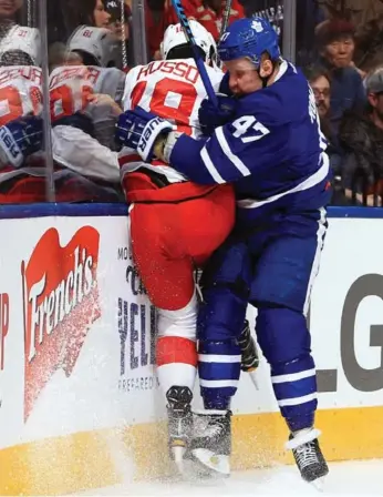  ?? VAUGHN RIDLEY/GETTY IMAGES ?? Detroit’s Robbie Russo is checked by the Maple Leafs’ Leo Komarov at the Air Canada Centre on Tuesday.