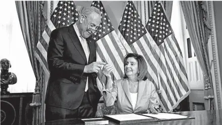  ?? J. SCOTT APPLEWHITE/AP ?? Senate Minority Leader Chuck Schumer joins House Speaker Nancy Pelosi as she signs the budget package Thursday.