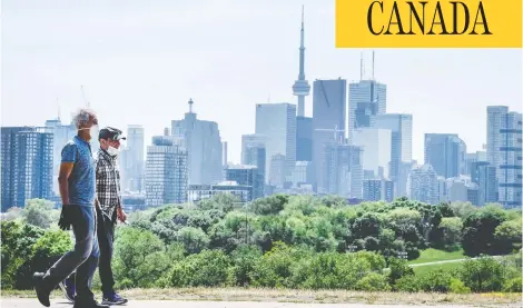  ?? PETER J THOMPSON / FOR NATIONAL POST ?? Pedestrian­s in masks walk along Toronto’s Broadview Avenue on Tuesday. The Toronto area has been hit much harder than elsewhere in Ontario.