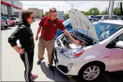  ?? ASSOCIATED PRESS ?? IN THIS JUNE 13 PHOTO, Mark Miller Toyota salesman Doug Lund shows the engine of a Prius C hybrid to customer Mary Jean Jones, in Salt Lake City.