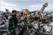  ?? ADAM DEAN / NEW YORK TIMES ?? Soldiers on Wednesday look on as rescue workers attempt to recover the body of a child killed in last Friday’s earthquake and tsunami in the Balaroa neighborho­od of Palu, Indonesia.