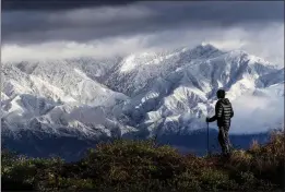  ?? WATCHARA PHOMICINDA — THE ORANGE COUNTY REGISTER ?? Frank Huong takes a break from hiking to enjoy a view of snow-capped San Gabriel Mountains from Hidden Hills trail in Chino Hills on Friday.