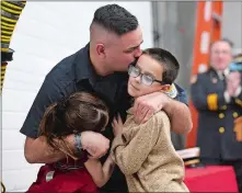  ?? SARAH GORDON/THE DAY ?? Firefighte­r Keegan Costello hugs his son Korbin, 8, and daughter Kambrie, 6, after they pinned him on Wednesday.