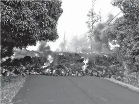  ??  ?? A lava flow moves across Makamae Street in the Leilani Estates subdivisio­n near Pahoa on the Big Island of Hawaii. The Kilauea volcano has destroyed more than two dozen homes since it began spewing lava hundreds of feet up last week. Residents who...