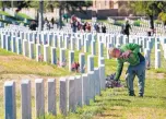  ??  ?? Preston Miles, of Santa Fe, was among dozens of people who honored our nation’s deceased veterans by placing U.S. flags on their graves at the Santa Fe National Cemetery on Friday.