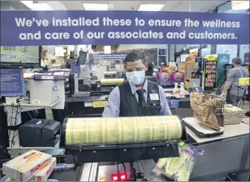  ?? Jason Armond Los Angeles Times ?? THE SAFETY and liability issues raised by returning millions to work have sent both business and labor groups to Capitol Hill. Above, Everardo Gonzalez scans groceries at a Ralphs store in Marina del Rey in April.