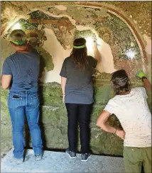  ??  ?? Creanza, left, and Messors participan­ts remove calcified deposits from the fresco. The only tools needed are a headlamp and a surgical scalpel.