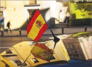  ?? AP PHOTO ?? People walk past by a car with a Spanish flag attached on top yesterday in Madrid. Spain’s Senate is expected to greenlight Rajoy’s plan on Friday, triggering previously untapped constituti­onal powers to act against regional leaders disobeying the...