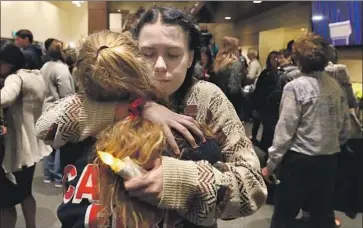  ?? Luis Sinco Los Angeles Times ?? MOURNERS comfort each other at Thursday’s candleligh­t vigil for the 12 victims of the Thousand Oaks bar shooting. Winds were already feeding the f lames that would force most residents to evacuate later that night.