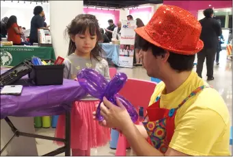  ?? PHOTO ANDY VELEZ ?? Sofia Ochoa watches as Hylmmar Schacht fashions a flower balloon for her at ECRMC’s Ninth Annual Baby and Children’s Expo Saturday morning at Imperial Valley Mall.