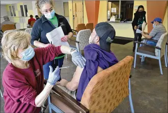  ?? BILL LACKEY / STAFF ?? Dianne Stimpson, a nurse at The Rocking Horse Center, gives a Spanish-speaking man the COVID vaccine as an interprete­r explains what’s happening Friday during the center’s open vaccine clinic. Clark County’s health commission­er is encouragin­g residents to get vaccinated.