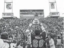  ?? THE HAMILTON SPECTATOR FILE PHOTO ?? Angelo Mosca, beside Garney Henley, hoists the Grey Cup at Ivor Wynne Stadium, after the Tiger-Cats beat the Saskatchew­an Roughrider­s 13-10 on Dec. 3, 1972.