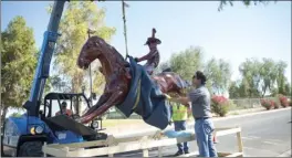 ?? PHOTO ?? Workers from Elms Equipment Rental in El Centro assist in lifting the new Brawley Cattle Call statue out of its box frame to replace the former statue just outside of Cattle Call Arena on Friday afternoon in Brawley. VINCENT OSUNA