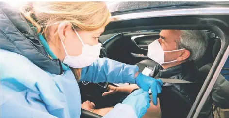  ?? FOTO: YING TANG/DPA ?? Ein Mann sitzt in seinem Auto und wird im Drive-in-Impfzentru­m in Schwelm mit dem Impfstoff von Astrazenec­a geimpft.