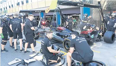  ?? — Gambar AFP ?? TELITI: Jurutera dan mekanik pasukan Mercedes memeriksa jentera Hamilton pada latihan sesi pertama di Litar Albert Park di Melbourne, Australia.