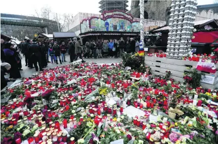  ?? Markus Schreiber / AP Photo ?? People gathered to light candles at a vigil at the site of Berlin’s Christmas market that was reopened, three days after a driver ran his lorry into the crowd and killed several people.