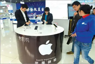  ?? LONG WEI / FOR CHINA DAILY ?? Customers choose iPhone handsets at a China Mobile Ltd branch in Hangzhou, Zhejiang province. China Mobile and Apple Inc have signed a multiyear agreement to bring the latest Apple smartphone models to the mainland market.