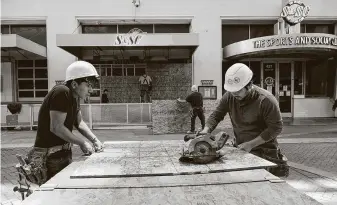  ?? Jeff Dean / AFP via Getty Images ?? Workers board up businesses in downtown Louisville, Ky., on Tuesday in anticipati­on of the results of a decision about charges in the death of Breonna Taylor.