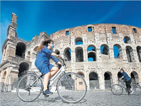  ?? /AFP ?? Bumpy ride: Cyclists ride past the Colosseum in Rome on May 8 2020, during Italy’s lockdown aimed at curbing the spread of Covid-19, which has hit the country particular­ly hard and left it facing a tough economic future.