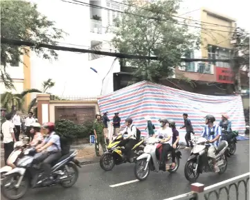  ?? — AFP photo ?? A tarpaulin covers the damaged facade of a police station in Ho Chin Minh city following an explosion near the site of massive protests in the city earlier this month.