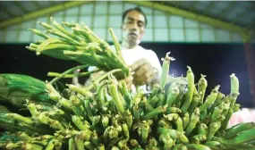  ?? PHILIPPINE STAR/MIGUEL DE GUZMAN ?? A MAN tends to the vegetables in his stall at the TienDA Farmers and Fisherfolk­s Outlet, a pop-up market set by the Department of Agricultur­e.