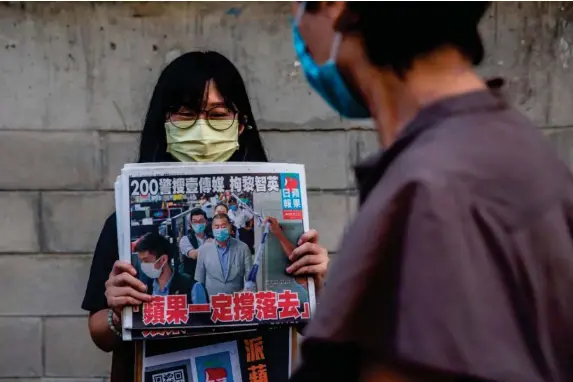  ??  ?? A Hong Kong resident holds up a copy of ‘Apple Daily’ yesterday (AFP/Getty)
