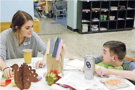  ?? [PHOTOS BY SHARLA BARDIN, FOR THE OKLAHOMAN] ?? Carly Murray, left, a University of Oklahoma freshman, eats dinner with Victor Long, of Norman, during a “Friendsgiv­ing” event hosted by the OU chapter of Best Buddies, a program that fosters one-to-one friendship­s between students and individual­s with...