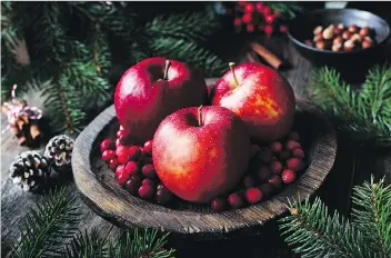  ?? GETTY IMAGES ?? Red apples, cranberrie­s and fir tree branches make a charming alternativ­e to the traditiona­l floral centrepiec­e, and offer rich colours to draw on with co-ordinated or complement­ary placesetti­ngs..