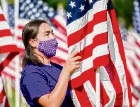  ?? Colonial Flag Foundation ?? A volunteer places an American flag in a field.