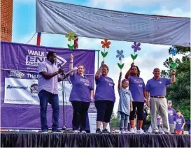  ??  ?? Participan­ts of the 2017 Walk to End Alzheimer’s hold different-colored flowers during the “Promise Garden” ceremony. Orange represents people who support the cause and the vision of a world without Alzheimer’s disease. The purple flower represents...